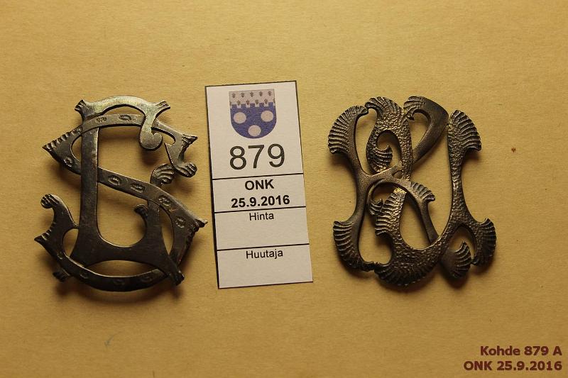 k-0879-a.jpg - Kohde 879, l�ht�hinta: 10 &euro; 2 solkea Lotta Sv�rd, KU Koristeelliset pakotetut monogrammisoljet, takana lenkit kiinnityst� varten. Toinen monogrammi "LS" 55x45mm, toinen "KU" 52x42mm, kunto: 8, 8